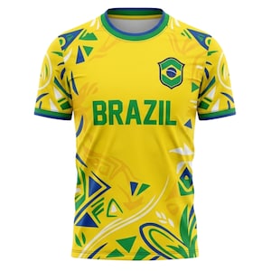 Op de afbeelding: Geel Brazili&euml; voetbalshirt met groene en blauwe accenten. Het woord "BRAZIL" staat in grote groene letters op de voorkant, onder het teamembleem. Het shirt heeft een ronde hals en korte mouwen.