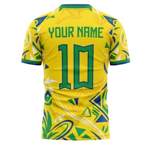 Op de afbeelding: Geel voetbalshirt met groene en blauwe accenten. De achterkant toont het nummer 10 in groen, met de tekst "YOUR NAME" erboven. Het shirt heeft een patroon en groene afwerking.