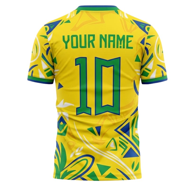 Op de afbeelding: Geel voetbalshirt met groene en blauwe accenten. De achterkant toont het nummer 10 in groen, met de tekst "YOUR NAME" erboven. Het shirt heeft een patroon en groene afwerking.