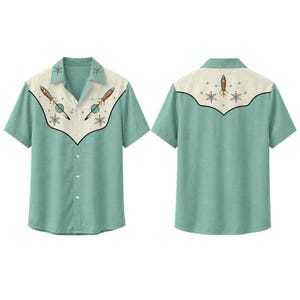 May include: A short-sleeve button-down shirt in light green with a cream-colored western-style yoke on the front and back. The yoke features a graphic print of rockets, planets, and starburst shapes in red, blue, and black ink on the fabric.
