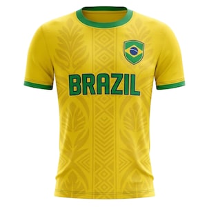 May include: A yellow Brazil soccer jersey with green accents on the collar and sleeves. The word "BRAZIL" is across the chest in green block letters. A shield with the Brazilian flag is on the upper chest.