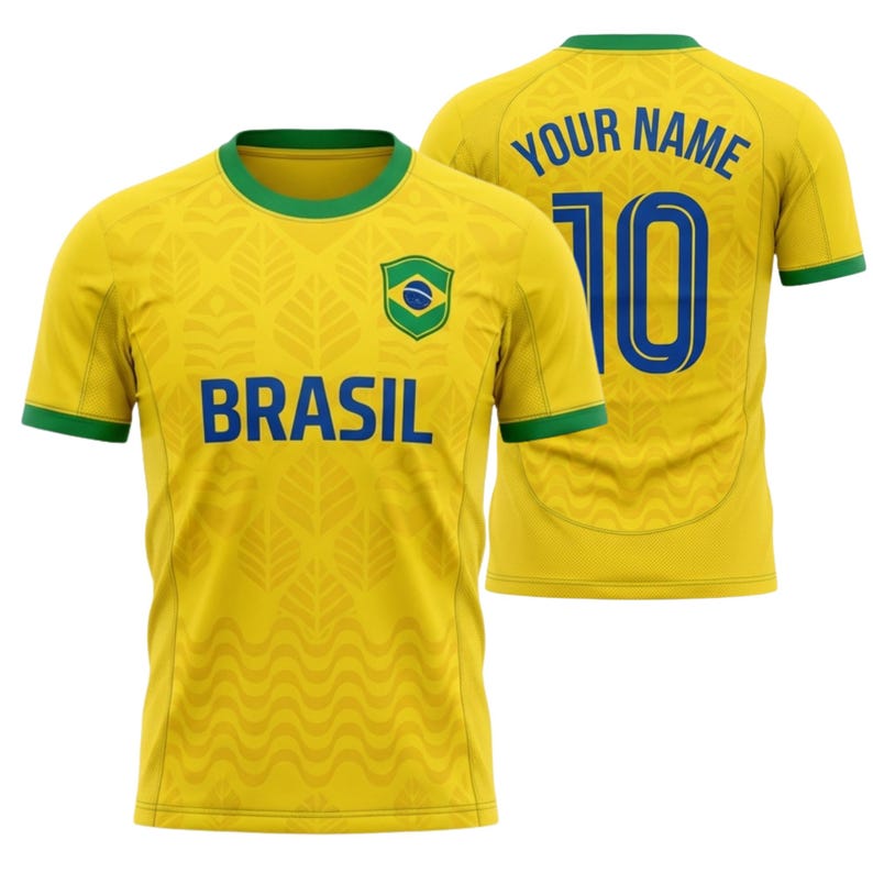 Puede incluir: Camiseta de f&uacute;tbol amarilla de Brasil con ribetes verdes y la palabra "BRASIL" en azul. La camiseta presenta la bandera brasile&ntilde;a y un estampado de hojas. La parte trasera de la camiseta tiene el n&uacute;mero 10 y el texto "YOUR NAME" en azul.