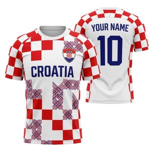 May include: White and red checkered Croatia soccer jersey with the word "CROATIA" in navy blue. The jersey has a Croatian coat of arms on the chest and the number 10 on the back. The back of the jersey also has the text "YOUR NAME".