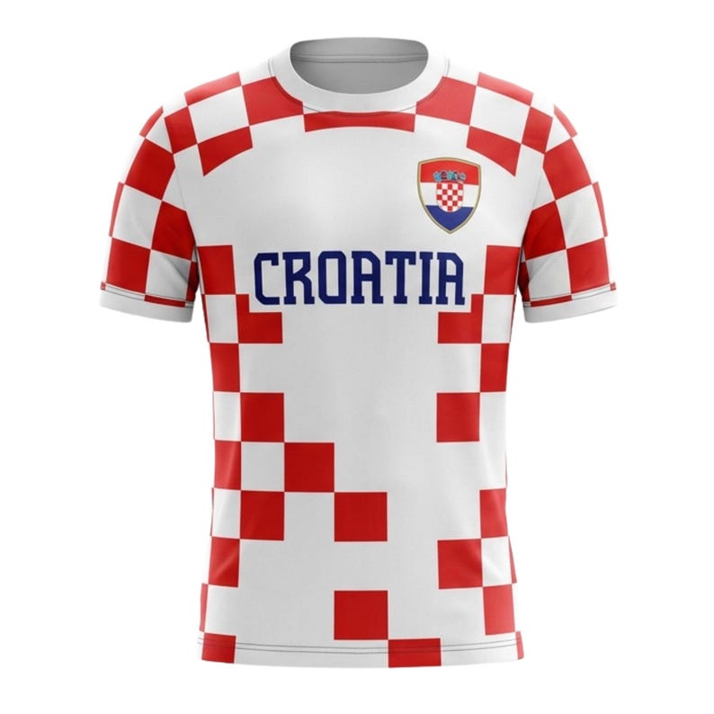 Op de afbeelding: Wit T-shirt met rood-wit geblokt patroon op de schouders en mouwen. Het woord "CROATIA" is in blauw op de borst gedrukt. Een Kroatisch wapen staat op de bovenborst.