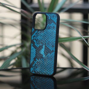 May include: A black phone case with a blue snakeskin pattern. The case has a sleek design and is made of a durable material. The case is designed to protect the phone from scratches and other damage.