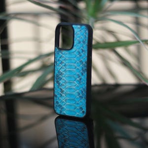 May include: A black phone case with a vibrant blue snakeskin pattern. The case has a sleek design and is made of a durable material. The phone case is designed to protect the phone from scratches and damage.