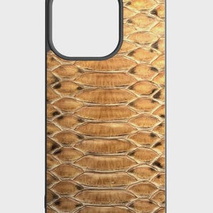 May include: A phone case featuring a brown snakeskin pattern with a black border. The case has a cutout for the camera and is designed to fit a smartphone. The snakeskin design has a textured appearance.