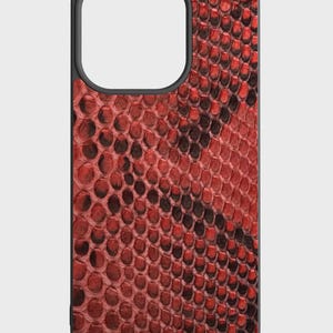 May include: A smartphone case with a red and black snakeskin pattern. The case has a black border and a cutout for the camera. The snakeskin design is detailed and textured, giving it a realistic appearance.