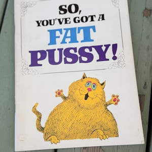 May include: A vintage book cover with the text "SO, YOU'VE GOT A FAT PUSSY!" in blue and purple. The cover features a cartoon illustration of a large, yellow cat with pink paws and a smiling face.