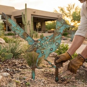 Peut inclure: Une décoration de jardin en métal en forme de grand géocoucou avec une patine turquoise et cuivre vieillie, ornée de motifs géométriques et solaires découpés au laser sur tout le corps, fixée au sol par deux tiges métalliques robustes.