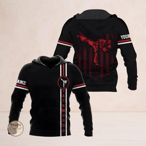 May include: Black Taekwondo hoodie with a red and white stripe design. The front features a Taekwondo graphic and the word "TAEKWONDO" vertically. The back displays a red graphic of a Taekwondo practitioner against a red and white striped background. The sleeves have white stripes with red accents.