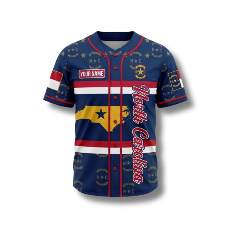 May include: A navy blue baseball jersey with red and white stripes. The jersey features the North Carolina state outline in gold, the text "North Carolina" in white, and the text "YOUR NAME" on the chest. The sleeves have a flag design.