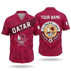 May include: A maroon button-up shirt featuring the word "QATAR" in white on the front. The shirt has a repeating pattern of boats and buildings. The back of the shirt displays the text "YOUR NAME" above a circular emblem.