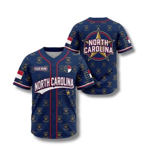 May include: A navy blue baseball jersey with red and white detailing. The jersey displays the text "NORTH CAROLINA" and a star graphic. The back of the jersey has a large star graphic with the words "NORTH CAROLINA". It has a button-up front and short sleeves.