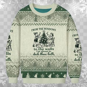 以下が含まれることがあります： クリーム色のクリスマスセーター。緑と白の雪の結晶模様。前面には、子供たちがクリスマスツリーを飾っているグラフィックがあり、「From the windows to the walls I'm about to deck these halls」というテキストが書かれています。
