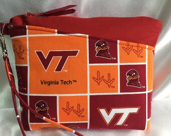 Puede incluir: Una bolsa con cremallera roja y naranja con un patrón repetido del logotipo de Virginia Tech, una mascota de pájaro y un diseño de huella. La bolsa tiene un tirador de cremallera rojo con una raya blanca.