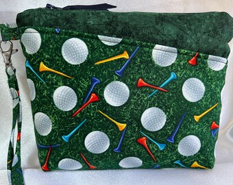 Puede incluir: Bolsa verde con cremallera con estampado de bolas de golf y tees. La bolsa tiene cierre de cremallera y una correa de muñeca.