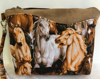 Puede incluir: Un bolso de mano de gamuza marrón con cierre de cremallera y una correa de cadena dorada. La parte delantera del bolso tiene un estampado colorido de caballos.
