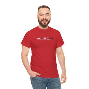 May include: A red t-shirt featuring the text "FLAT 6 MADE IN STUTTGART" in white and grey. The shirt is short-sleeved and made of a soft material.