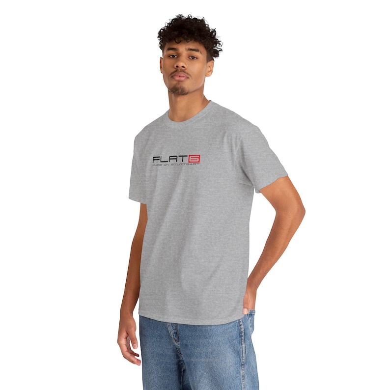 May include: A light grey t-shirt featuring the text "FLAT 6" in black and red. The shirt is made of a soft material and has a crew neck. The text "POWERED BY STUTTGART" is below the main text.