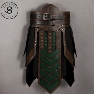 Puede incluir: Una prenda de cuero marrón y negro con un diseño de chevrón verde. La prenda tiene un cinturón con una hebilla plateada y está adornada con remaches. El logotipo de Leather Supply está en la esquina superior izquierda.