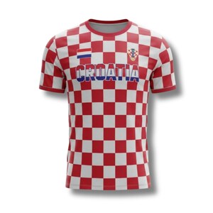 May include: A red and white chequered Croatia football shirt. The shirt displays the word "CROATIA" in blue block letters, the Croatian flag, and emblem. It has short sleeves and a crew neck. The design is a classic Croatian pattern.