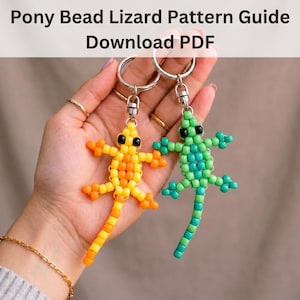 Peut inclure: Deux porte-clés en forme de lézard en perles, l'un orange et jaune, l'autre vert et bleu, sont présentés. Les lézards sont faits de perles et ont des yeux noirs. Le texte "Pony Bead Lizard Pattern Guide Download PDF" est en haut.