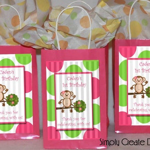 May include: Three pink and white gift bags with green polka dots and a monkey graphic. The bags have a white handle and a label that says "Caden's 1st Birthday" and "Thank you for celebrating with us!"