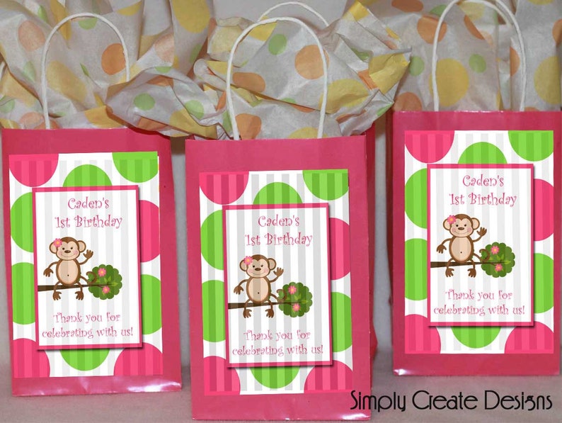 May include: Three pink and white gift bags with green polka dots and a monkey graphic. The bags have a white handle and a label that says "Caden's 1st Birthday" and "Thank you for celebrating with us!"