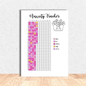May include: A white Anxiety Tracker print with a grid for tracking daily anxiety levels. The title "Anxiety Tracker" is in cursive. The tracker uses pink, yellow, and purple to indicate anxiety levels. A floral illustration is in the upper right corner.