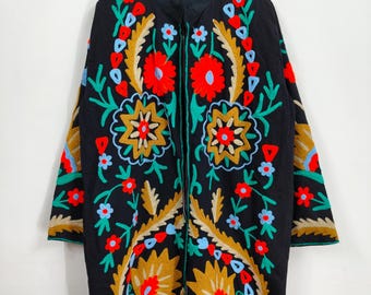 May include: Black embroidered coat with a floral design. The coat features a vibrant display of red, yellow, blue, and green floral embroidery. The coat is hanging on a wooden hanger.