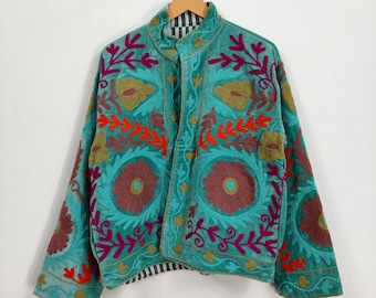 May include: Teal jacket with intricate floral embroidery in shades of red, purple, and gold. The jacket features a high collar and a striped lining. The embroidery creates a striking contrast against the teal fabric.