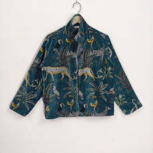 May include: Teal velvet jacket with a jungle print featuring leopards, zebras, and parrots. The jacket has a collared neckline and a full-length zip. The sleeves are long and the jacket is hanging on a white background.
