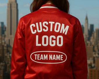 May include: Red satin bomber jacket with white trim and the words "CUSTOM LOGO" and "TEAM NAME" in white lettering. The jacket is shown against a cityscape background.
