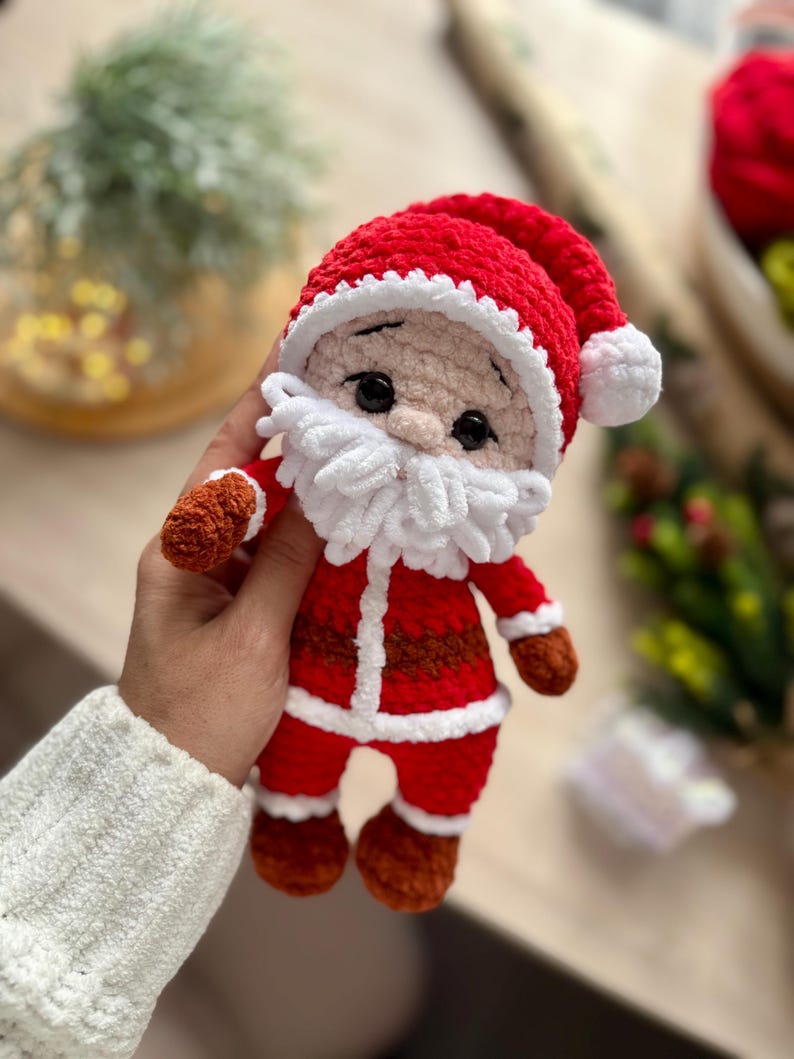 Puede incluir: Mu&ntilde;eco de Pap&aacute; Noel tejido a ganchillo, rojo y blanco. Tiene barba blanca, manos y pies marrones, y ojos negros. Un gorro rojo completa el dise&ntilde;o. Una decoraci&oacute;n navide&ntilde;a festiva.