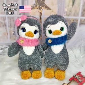May include: Two handmade crochet penguin dolls. One penguin has a pink bow and scarf, the other a blue scarf. Both have button accents and yellow feet. The text "Crochet pattern PDF" is in the upper left corner with a US flag.