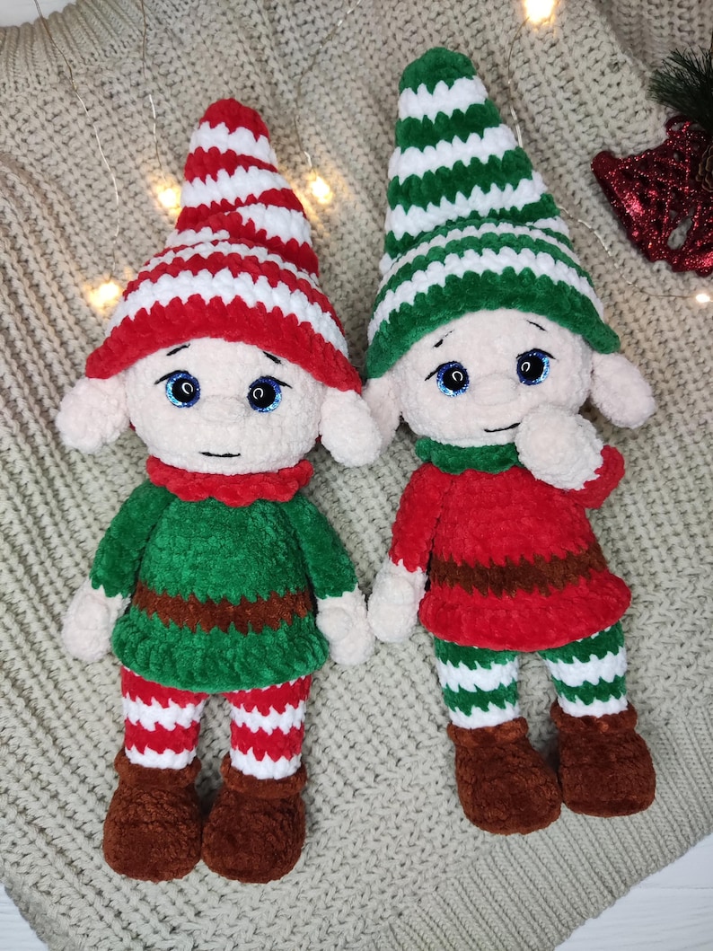 May include: Two handmade plush elf dolls. One elf wears a red and white striped hat, a green tunic, and red and white striped pants. The other elf wears a green and white striped hat, a red tunic, and green and white striped pants. Both have brown boots.