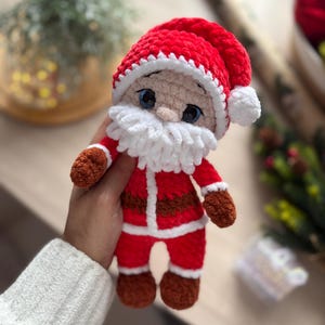 Puede incluir: Mu&ntilde;eco de Pap&aacute; Noel tejido a mano en rojo y blanco. El mu&ntilde;eco tiene un gorro rojo con ribete y pomp&oacute;n blancos, barba blanca y guantes y botas marrones. El mu&ntilde;eco mide aproximadamente 15 cm de alto.