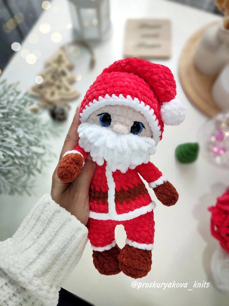 Puede incluir: Mu&ntilde;eco de Pap&aacute; Noel de felpa hecho a mano. El mu&ntilde;eco es principalmente rojo con ribetes blancos, barba blanca y gorro rojo con pomp&oacute;n blanco. Tiene ojos azules y guantes y botas marrones. El mu&ntilde;eco mide unos 15 cm de alto.