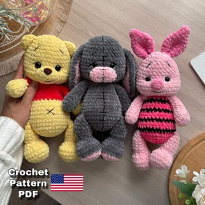 Könnte beinhalten: Drei handgefertigte gehäkelte Stofftiere: ein gelber Bär mit rotem Hemd, ein graues Häschen und ein rosa Schwein mit einem schwarz-rosa gestreiften Bauch. Das Bild enthält den Text "Crochet Pattern PDF" und eine amerikanische Flagge.