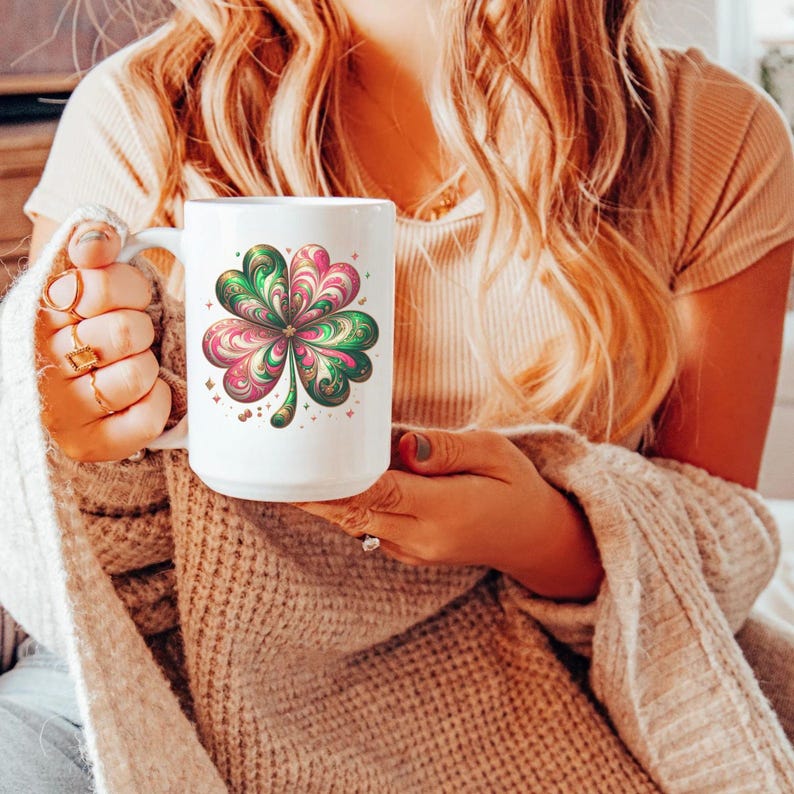 May include: White ceramic mug featuring a colorful four-leaf clover design in shades of pink, green, and gold. The clover is the focal point, surrounded by small star accents. The mug has a large handle.