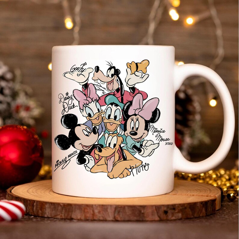 Puede incluir: Taza de cer&aacute;mica blanca con una colorida ilustraci&oacute;n de personajes de Disney, incluyendo Mickey Mouse, Minnie Mouse, Donald Duck, Daisy Duck, Goofy y Pluto. La taza tiene un asa grande y est&aacute; sobre una superficie de madera.