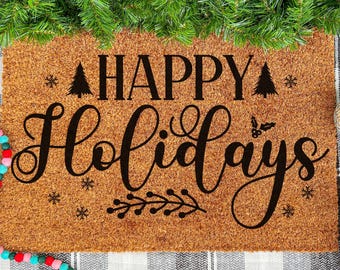 May include: A rectangular doormat with the words "HAPPY Holidays" in black script. The mat is brown with a textured surface. Decorative elements include a garland, disco balls, and evergreen branches.