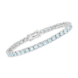 May include: A silver tennis bracelet featuring a series of round, light blue gemstones. The bracelet has a secure clasp and is designed to be worn around the wrist. The gemstones are evenly spaced and set in a silver band.