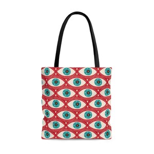 May include: A tote bag with a repeating pattern of stylized blue eyes on a red background. The eyes have white and blue details. The bag has black handles.
