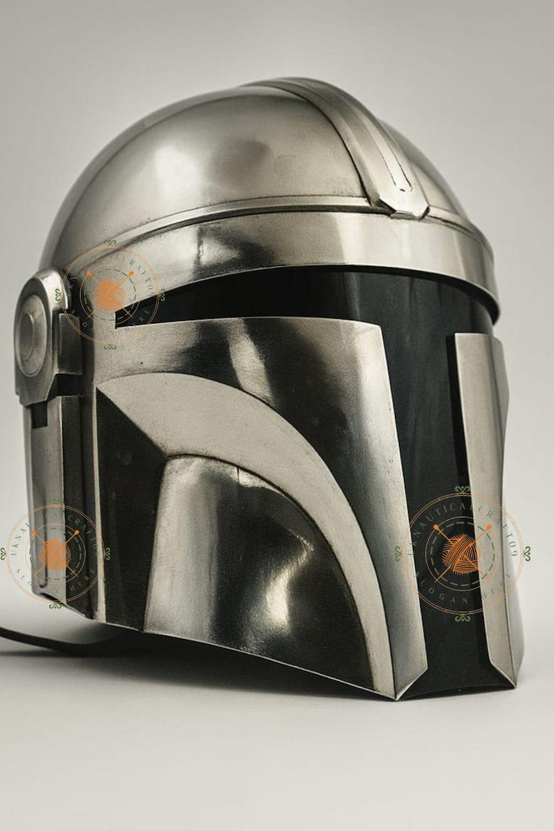 Op de afbeelding: Een zilveren Mandalorian helm met een afgeronde bovenkant en een T-vormig vizier. De helm heeft een donkergrijze frontplaat en is waarschijnlijk gemaakt van metaal. Het ontwerp doet denken aan een ruimtethema-personage.