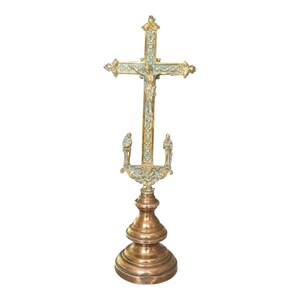 Peut inclure: Un crucifix en métal sur pied composé d'une croix dorée avec une figure centrale de Jésus, rehaussée de détails bleu clair. Deux petites figurines se tiennent à la base de la croix, fixée sur un piédestal étagé de couleur cuivre poli.