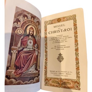 Peut inclure: Livre ouvert avec une illustration religieuse sur la page de gauche et du texte sur la droite. La page de gauche présente une figure couronnée assise, entourée d'anges. La page de droite affiche le titre "MISSEL DU CHRIST-ROI" et du texte supplémentaire.