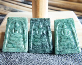 May include: Three rectangular jade pendants with a carved Buddha image in a seated position. The pendants are various shades of green and are displayed on a gray surface.