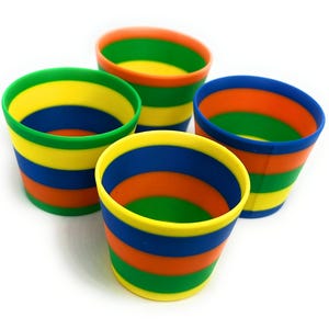 May include: Four colorful, striped cups in a vibrant arrangement. Each cup features horizontal bands of yellow, blue, orange, and green. The cups are set against a white background, highlighting their bright colors and playful design.
